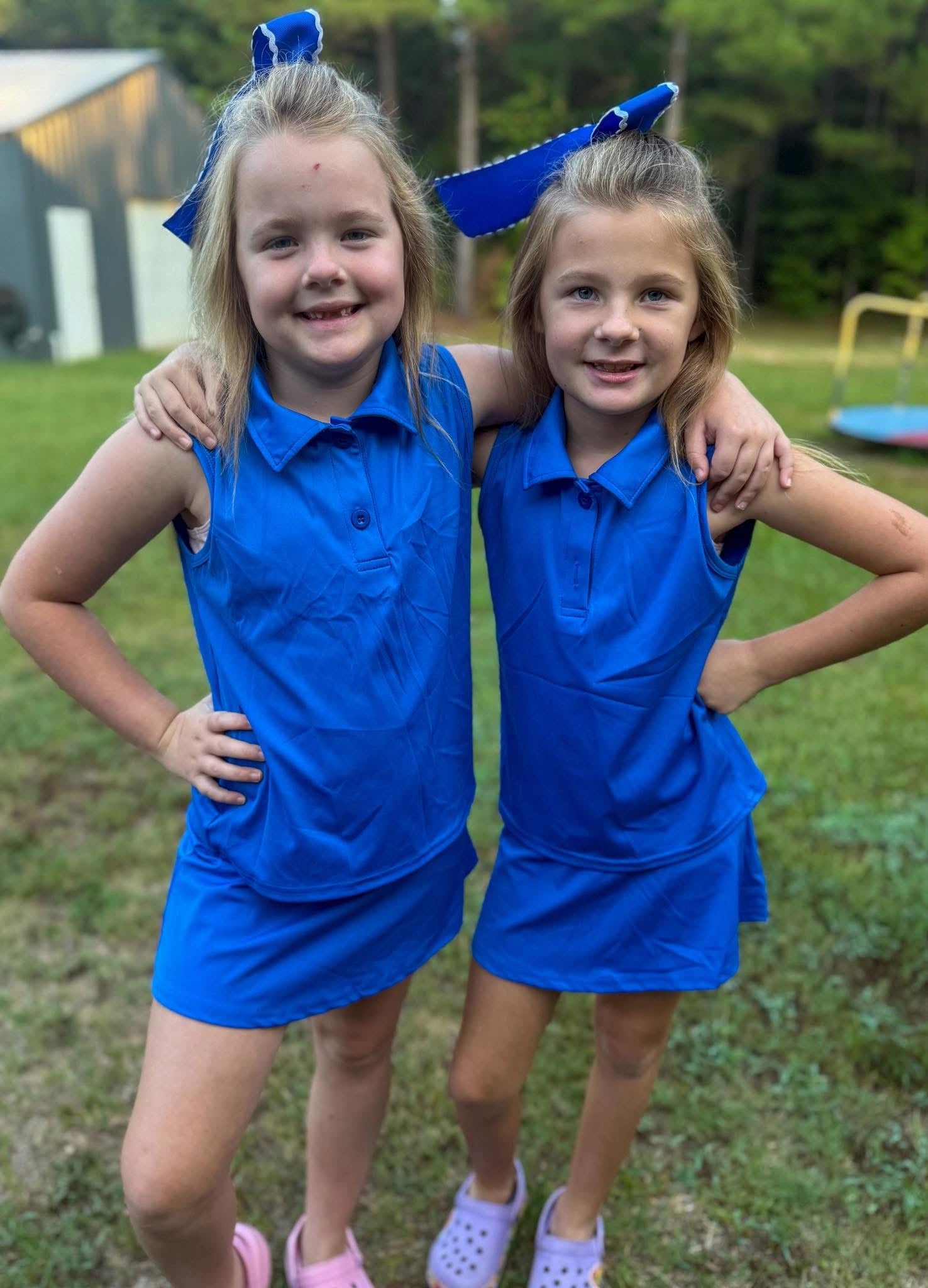 Girls wearing Bella’s Blue athletic polo skort set with sleeveless collared top and matching blue skort