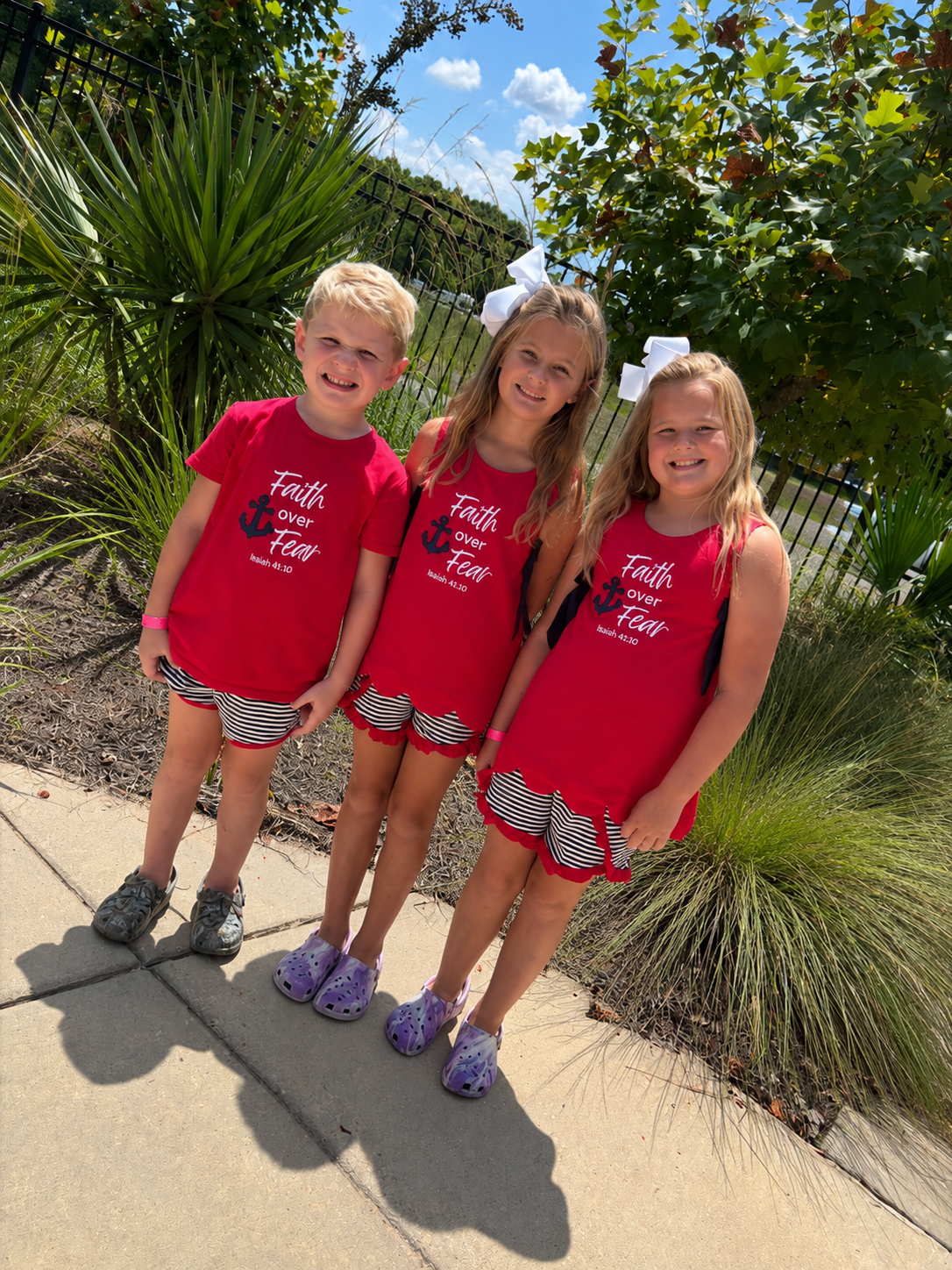 Children wearing Faith Over Fear sibling matching outfits with red embroidered tops and black and white striped shorts