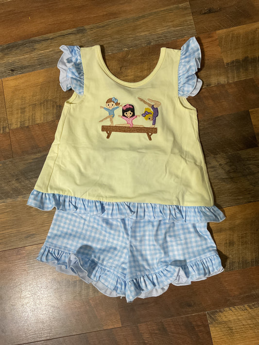 Flippin’ Sweet girls gymnastics short set with yellow embroidered gymnast top and blue gingham ruffle shorts.