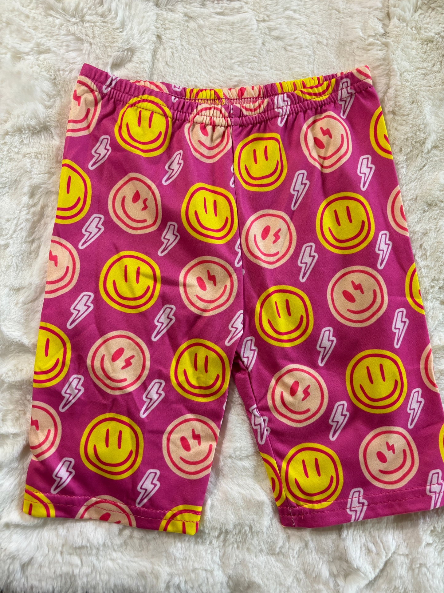Girls pink biker shorts with colorful smiley face and lightning bolt print