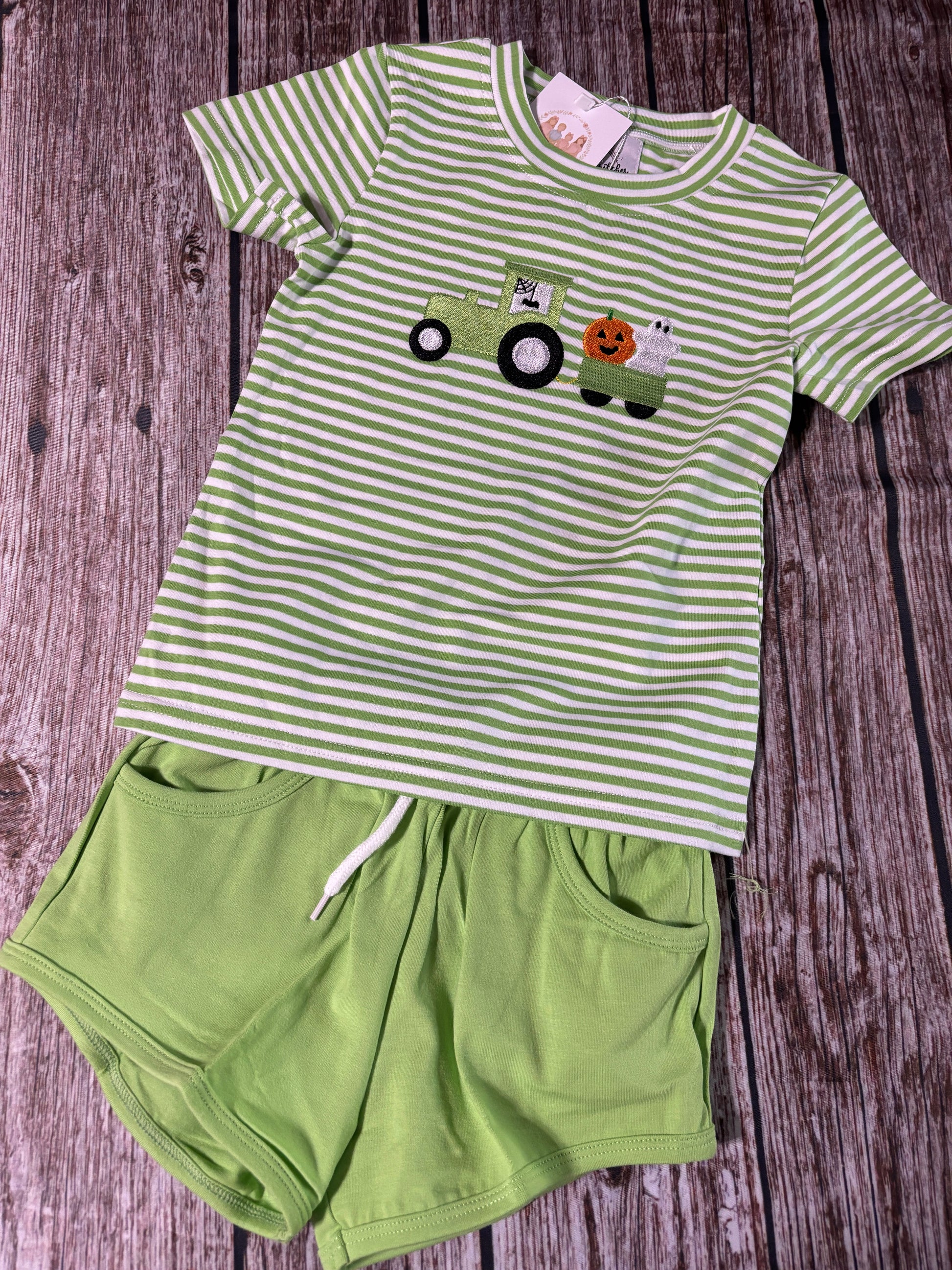 Harvest Haulers boys green striped short set with embroidered tractor pulling a pumpkin and ghost wagon and solid green shorts.