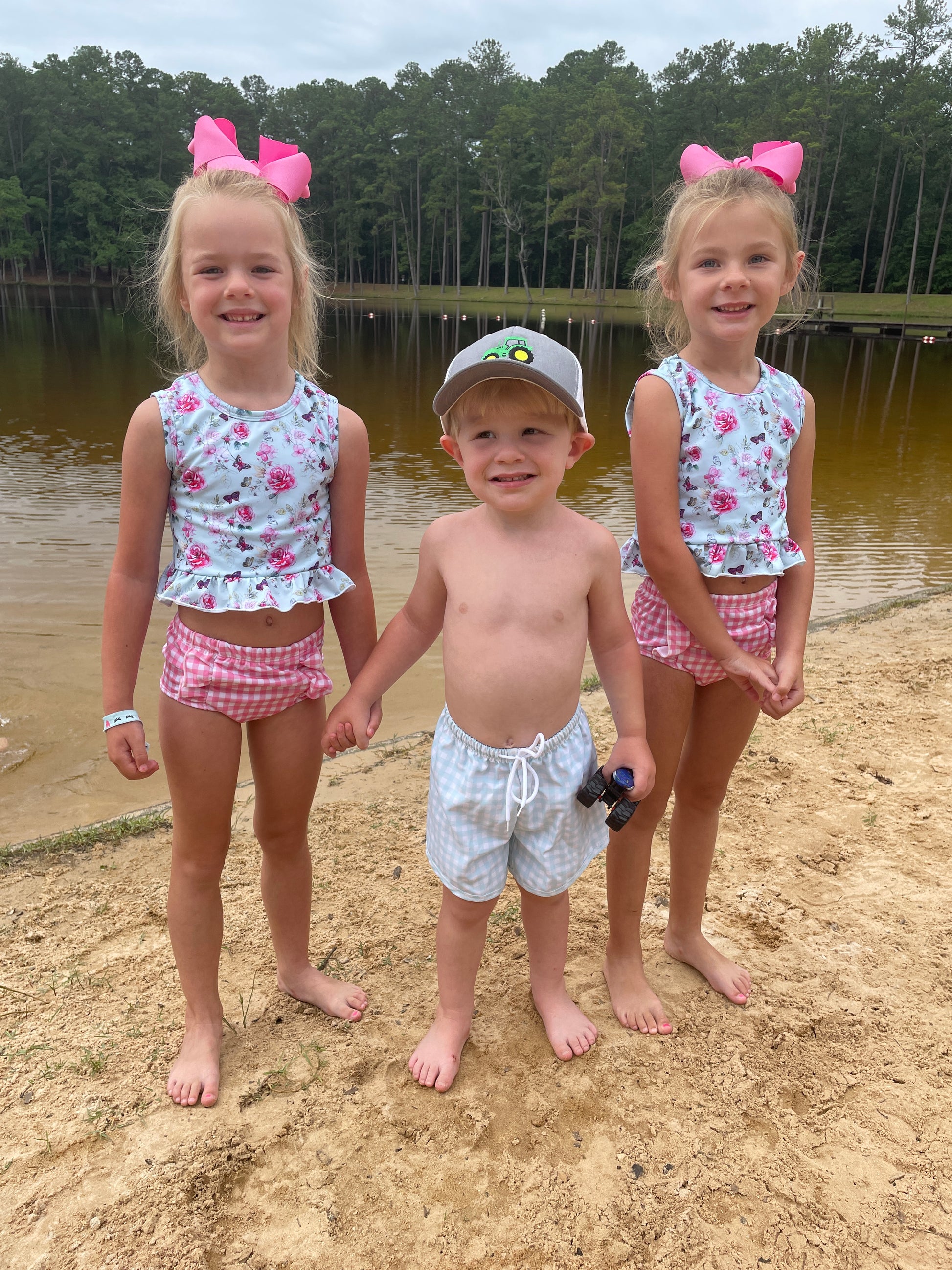 Summer Daze sibling matching swim collection with girls wearing two piece floral and gingham swimsuits and boy wearing coordinating swim trunks.